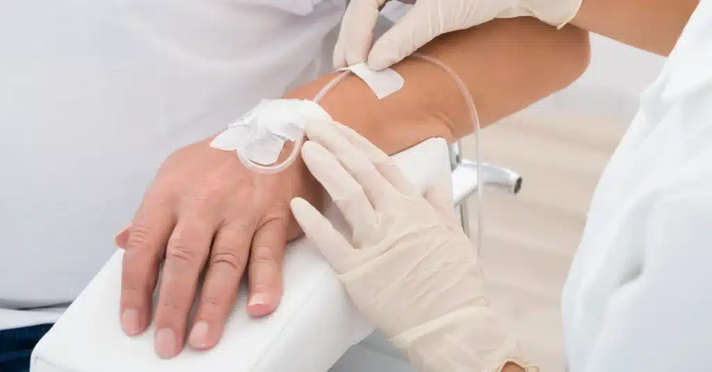 Healthcare professional wearing gloves carefully placing an IV line into a patient’s arm, symbolizing IV sedation, medical treatment, or intravenous therapy.