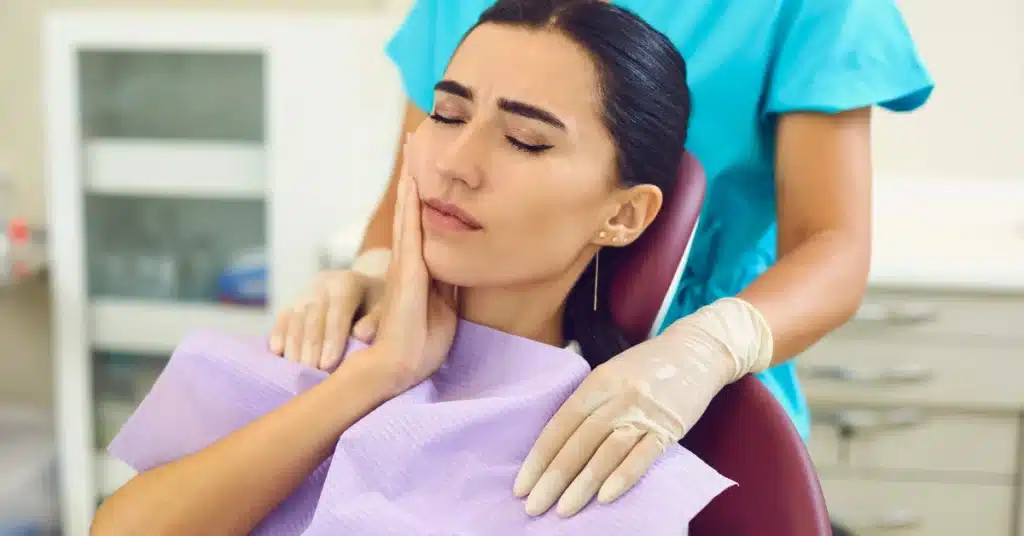 Female patient holding her jaw in pain during emergency dental visit for toothache