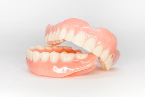 Types of dentures showing upper and lower acrylic teeth with gum-colored bases