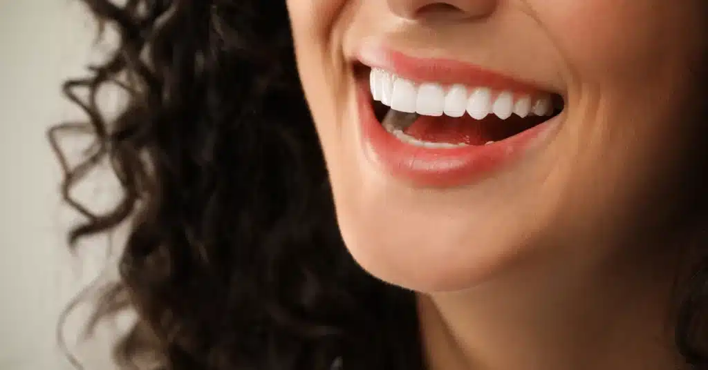 Close-up of a smiling woman with straight, white teeth, showcasing the results of professional dental care or cosmetic dentistry